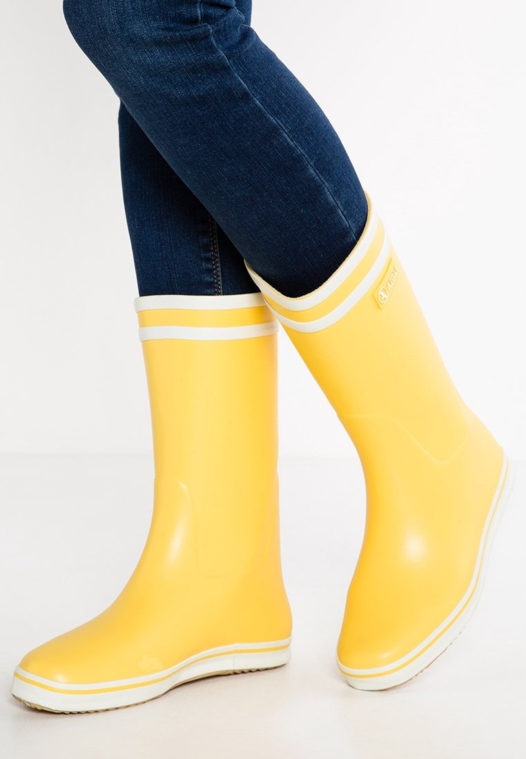 Bottes de pluie en caoutchouc jaune avec des rayures blanches horizontales en haut, texture lisse et brillante, bout arrondi, design ajusté à la cheville.