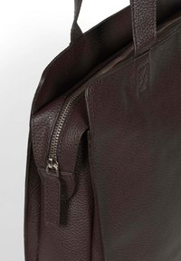 Borsa in pelle bordeaux scuro con superficie texture, dotata di due manici, chiusura a zip e tasca laterale.