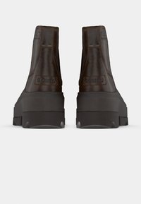 Bottines en cuir marron avec une finition texturée, dotées d'une semelle en caoutchouc noir et d'un logo en relief sur le talon.