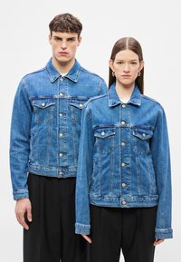 Világoskék farmerdzsekik patentos záródással, két mellzsebbel és hosszú ujjal. Az egyik dzseki rövidebb fazonú, míg a másik hosszabb.