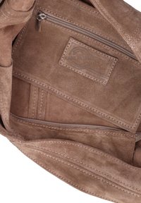 Interno di una borsa in suede marrone con una tasca con zip, texture liscia e dettagli di cucitura. Patch con logo visibile sulla fodera.