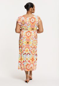 Robe maxi colorée et à motifs avec des manches courtes volantées, designs géométriques vifs en orange, bleu et jaune, longueur cheville, tissu lisse.