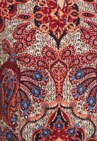 Röd och blå blommönster på en beige texturerad bakgrund; innehåller intrikata paisleymönster och utsmyckade detaljer genomgående.