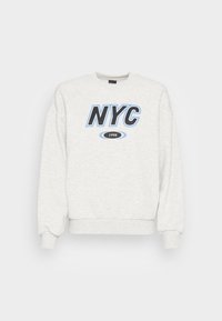 Sudadera gris claro con gráfico en negro y azul de "NYC" y el texto "1998". Presenta puños y cuello acanalados. Textura acogedora y suave.