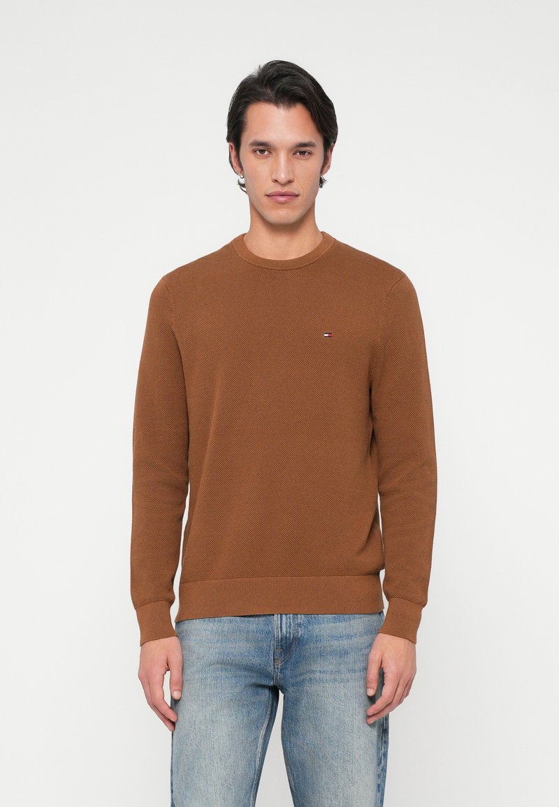 Brauner gestrickter Pullover mit Rundhalsausschnitt, langen Ärmeln und gerippten Bündchen. Verfügt über ein kleines Logo-Detail auf der Brust und einen strukturierten Stoff.