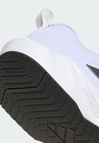 Keve könnyű atlétikai cipő, fehér hálós felsőrésszel, lapos fekete gumitalppal, amelynek texturált gripje van, és jellegzetes sarkú kiemeléssel.