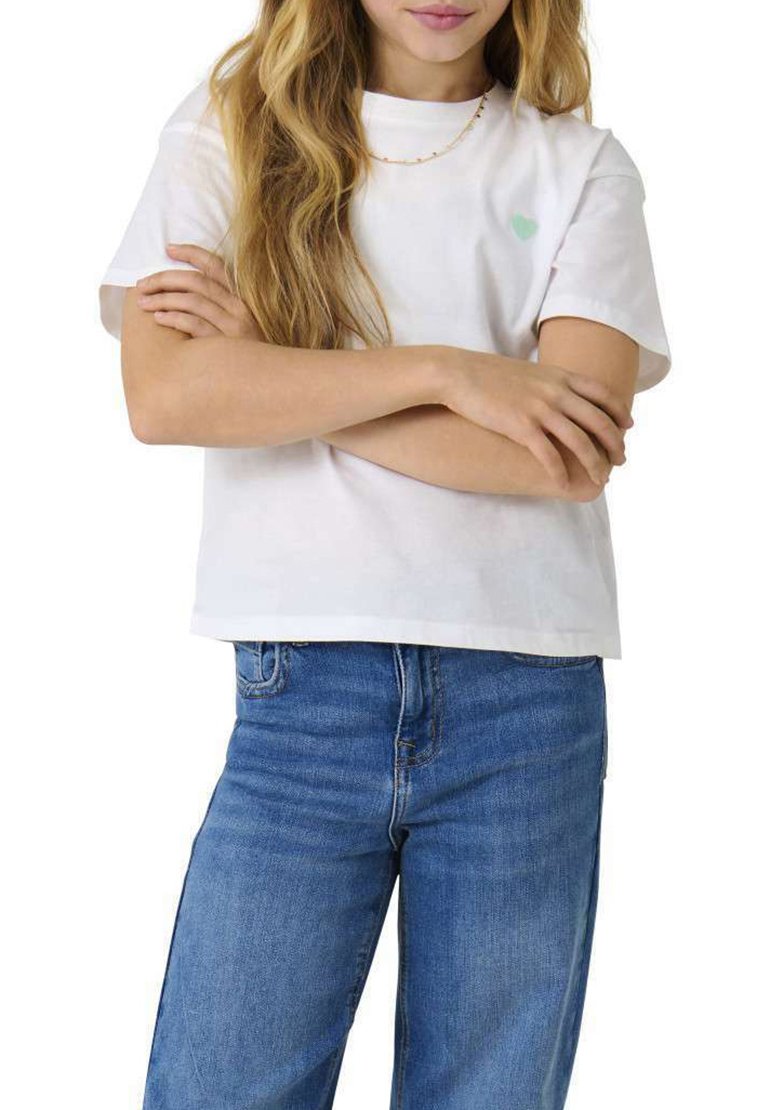 T-shirt en coton blanc à manches courtes, avec un petit logo de cœur vert sur la poitrine gauche, associé à un jean en denim bleu.