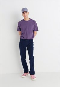 Purple cotton t-shirt, navy pants, pink sneakers, and a light blue cap. Simple design; casual fit with minimal accents.