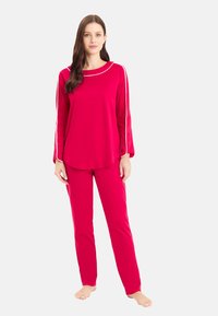 Rotes langärmeliges Oberteil und passende Hose mit weißen Akzenten. Weicher Stoff, lockere Passform, runder Halsausschnitt und gerades Bein-Design.