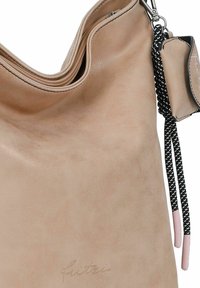 Bolso de hombro de piel beige con una textura suave, cierre de cremallera y un llavero. Acentuado con correas negras y rosas.