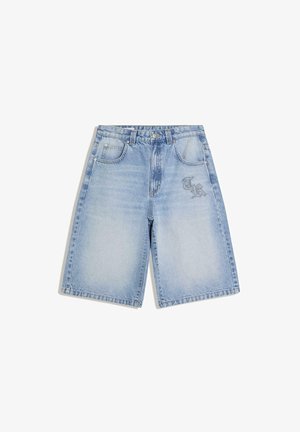 Short en denim bleu clair avec poches avant, passants pour ceinture, fermeture par bouton et zones délavées, avec un petit logo « TR » sur la cuisse droite.