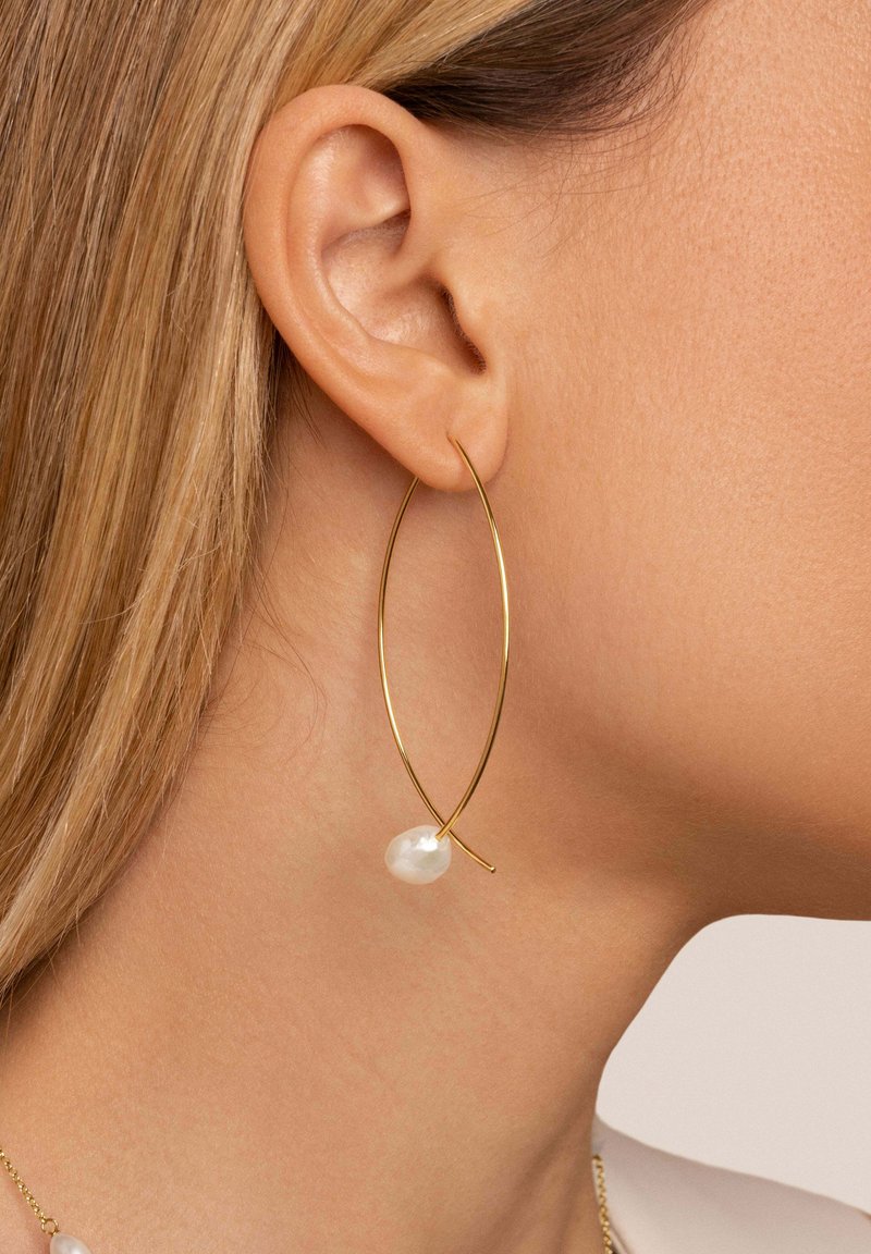Pendiente de aro dorado con forma alargada, adornado con una perla blanca. Acabado metálico suave con un diseño minimalista.