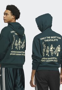 Tmavě zelená mikina s kapucí vyrobená z bavlny, s předními a zadními grafickými potisky v žluté barvě, znázorňující basketbalové hráče a text.