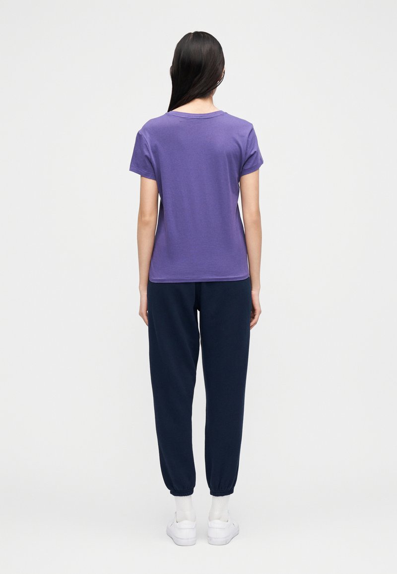 T-shirt violet à manches courtes associé à un pantalon de jogging bleu marine, avec une coupe décontractée et des poignets côtelés. Matière en coton avec une texture lisse.
