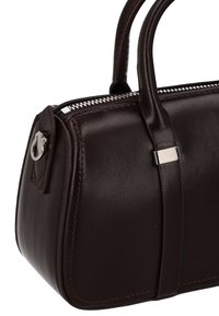 Braune Ledertasche mit abgerundeter Form, silberfarbenen Beschlägen, Reißverschluss und detaillierten Nähten entlang der Kanten.