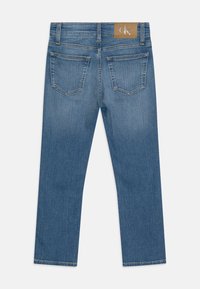 Jeans rectos azules con dos bolsillos traseros y un parche con el logotipo marrón de Calvin Klein en la cinturilla.