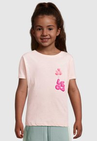 Lyserød kortærmet t-shirt med "LEON" i fede pink bogstaver og grafik af hjerteballoner på venstre side. Blødt bomuldsstof.