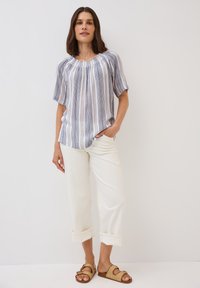 Gestreepte korte mouwen blouse in blauw en wit, ontspannen pasvorm met een geraffineerde halslijn; gecombineerd met witte broek met opgerolde mouwen en tan kleurige slide sandalen.