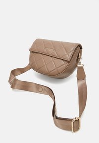 Steppelt bézs keresztpántú táska mágneses fedéllel, arany logóval és állítható selyem pánttal, amely márkajelzést tartalmaz. Simább bőrt textura.