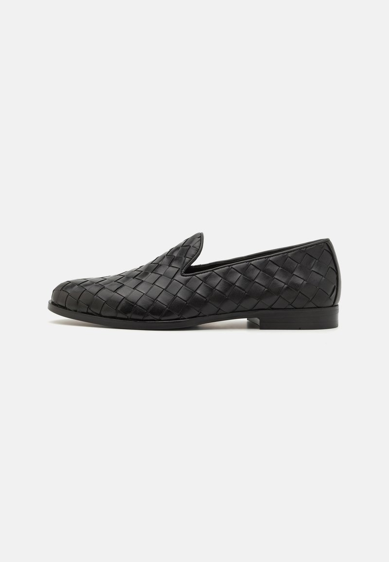 Black leather loafers with woven texture, rounded toe, low heel, and slip-on design. No visible hardware. Smooth surface with slight sheen.