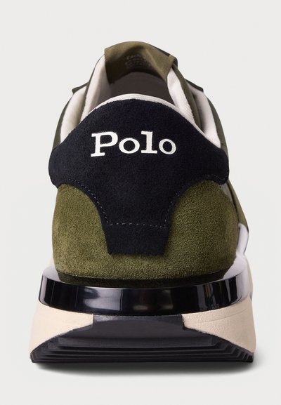 Green suede sneaker with black accents, white "Polo" logo on heel, thick black and cream sole, and soft textile lining.
