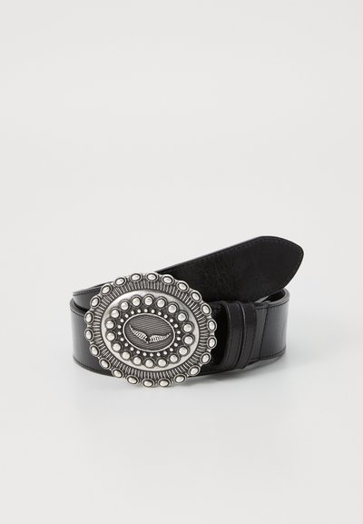 Black leather belt featuring a circular silver buckle with raised designs, bordered by decorative studs and an engraved central motif.