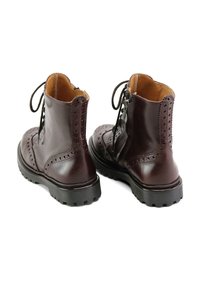 Botas de tobillo de cuero burdeos con detalles de brogue, punta redonda y una suela de goma negra gruesa; cuenta con cierres de cordones y cremallera lateral.