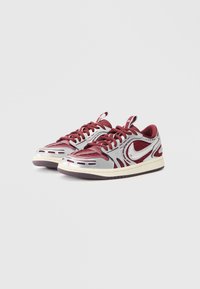 Bordo tenisice s srebrnim akcentima, mrežasti i sintetički gornji dio, prepoznatljiv swoosh logotip, teksturirani jezik i gumeni potplat s utorima.