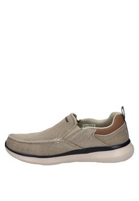 Scarpe slip-on beige con tomaia in tessuto testurizzato, accenti in pelle e suola imbottita. Presentano pannelli laterali elastici e dettagli di cucitura.