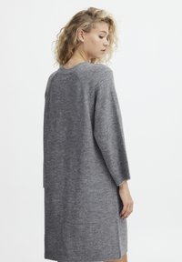 Rochie tricotată gri cu o croială relaxată, umeri lăsați și mâneci până la trei sferturi. Textură moale și slituri laterale pentru ușurința mișcării.