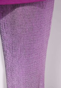 Gros plan d’un tissu texturé violet avec un tissage fin, légèrement brillant et une bande violette lisse et unie sur le bord supérieur.