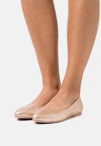 Ballerines nudes en cuir lisse, à bout arrondi, au design minimaliste et à semelle basse et plate.