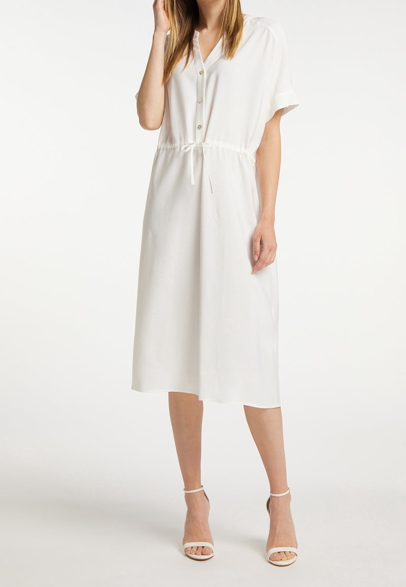 Weißes, mittel-lang geschnittenes Kleid mit kurzen Ärmeln, Knopfleiste und Kordelzug in der Taille. Hergestellt aus leichtem Stoff mit glatter Textur.