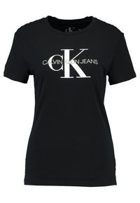Svart bomullströja med korta ärmar, med en vit logotypdesign som står "CALVIN KLEIN JEANS" och "CK" framträdande.