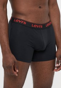 Schwarze Boxerbriefs aus Baumwolle mit einem roten Gummibund, der mit "Levi's"-Branding versehen ist. Das Design hat eine enge Passform und eine glatte Textur.