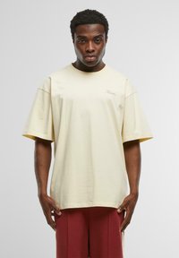 Lichtgele oversized katoenen T-shirt met korte mouwen en een ronde hals, met subtiele logo borduursels in een bijpassende kleur.