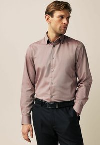 Helles braunes, gemustertes Hemd mit Button-Down-Kragen und langen Ärmeln. Kombinieren Sie es mit dunklen Hosen und einem schwarzen Gürtel für einen formellen Look.