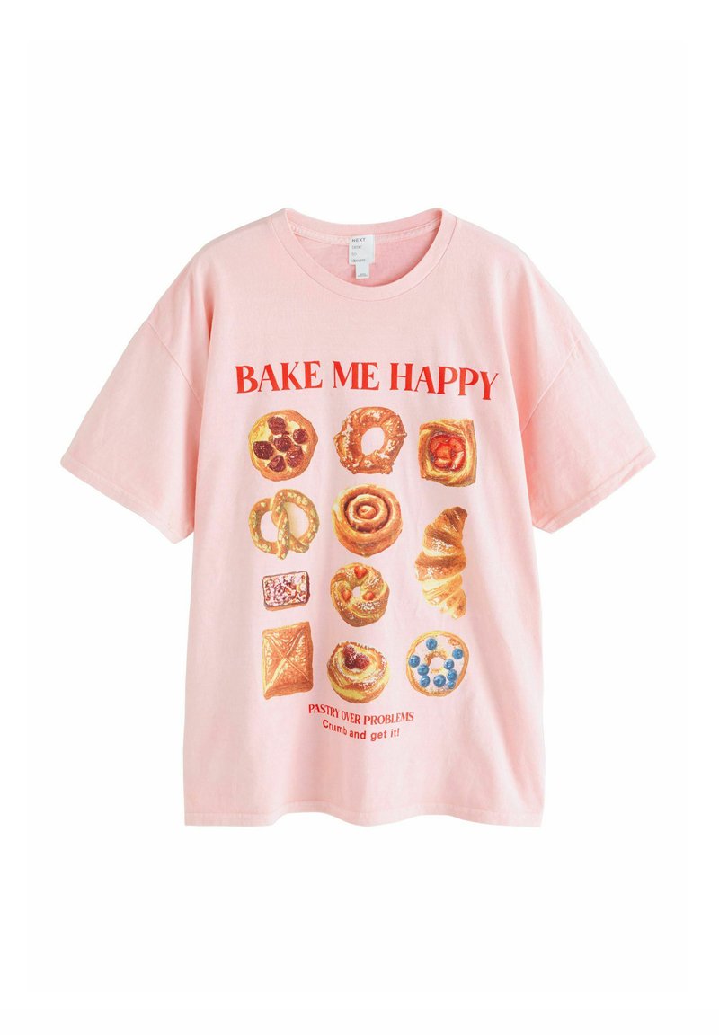 Pink t-shirt with red text "BAKE ME HAPPY" and illustrations of various pastries including a croissant, cinnamon roll, and fruit Danish.