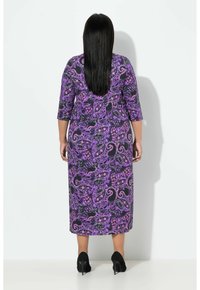 Purppuranvärinen maksimekko, jossa on paisley-kuviointi, 3/4-hihat ja rento istuvuus, yhdistettynä mustiin korkokenkiin.