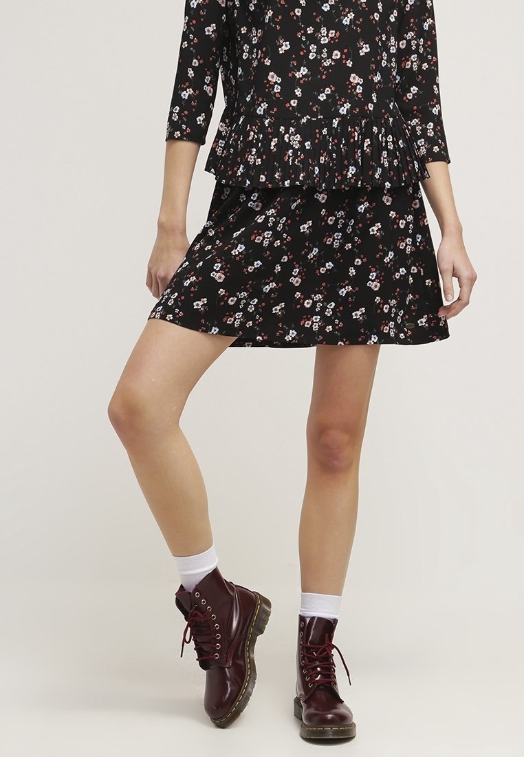 Černé květinové šaty s peplum lemem, vyrobené z jemného materiálu, s krátkými rukávy a vrstvenou sukní. Doplněné vínovými šněrovacími botami.