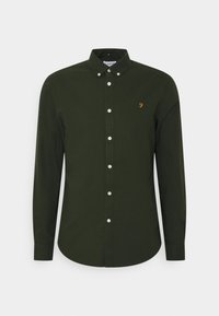 Chemise manches longues vert foncé avec boutons blancs, col boutonné et petit logo jaune "F" sur la poitrine gauche.