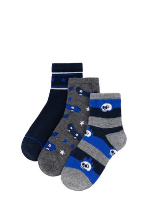 Tres pares de calcetines infantiles en tonos azules y grises; los diseños incluyen estrellas, monopatines y calaveras con cuernos.
