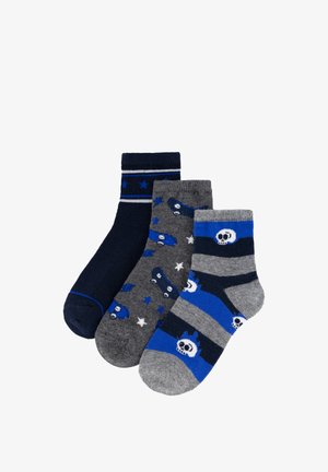 Tres pares de calcetines infantiles en tonos azules y grises; los diseños incluyen estrellas, monopatines y calaveras con cuernos.