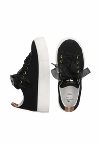 Sneaker in tela nera con suole in gomma bianca, occhielli dorati e lacci in raso neri. Presenta un'etichetta con logo e una texture morbida sulla parte superiore.