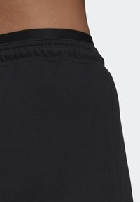 Černé sportovní šortky z měkké, texturované tkaniny. Mají elastický pas a šité detaily po stranách.