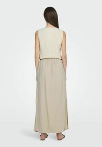 Vestido de dos piezas de lino beige que presenta una parte superior sin mangas con un escote redondo y una falda larga y fluida con una cinturilla elástica.
