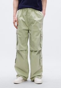 Ανοιχτό  πράσινο παντελόνι εργασίας με ελαστική μέση, πολλαπλές πλαϊνές τσέπες και χαλαρή εφαρμογή. Κατασκευασμένο από ελαφρύ, απαλό ύφασμα.