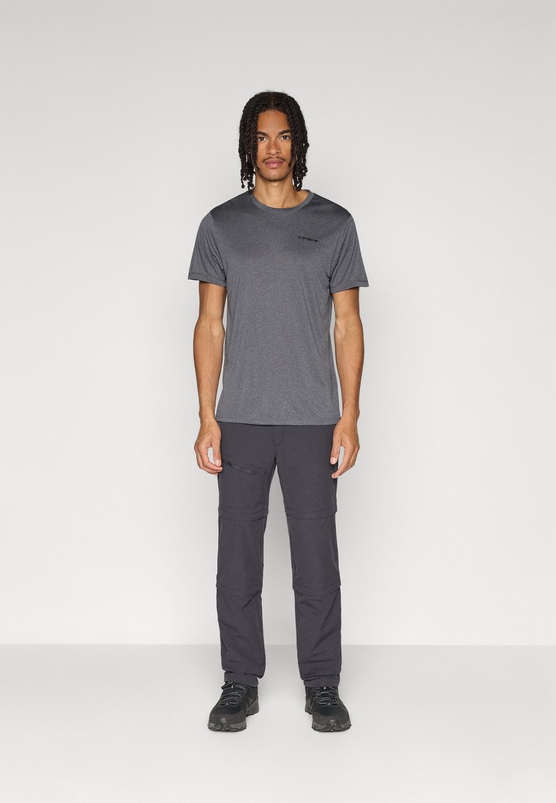 Grijze T-shirt met korte mouwen en een subtiel logo, gecombineerd met donkere cargobroeken met meerdere zakken en een gladde textuur. Zwarte wandelschoenen.