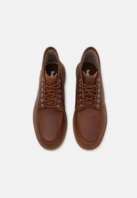 Pantofi din piele maro cu vârful rotund, guler căptușit, design cu șireturi și cusături contrastante. Talpă din cauciuc pentru aderență și durabilitate.