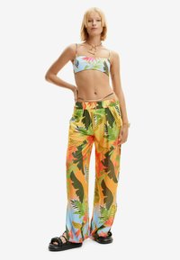 Kolorowy top w kwiatowy wzór i szerokie spodnie w odcieniach żółci i niebieskiego. Lekka tkanina o gładkiej fakturze oraz elastyczny pas.